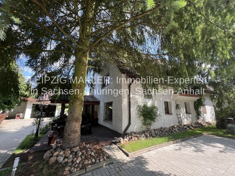 Einstöckiges Wohnhaus mit weißer Fassade, Satteldach und Klinkergiebel, umgeben von großen Bäumen, Splau in Bad Schmiedeberg